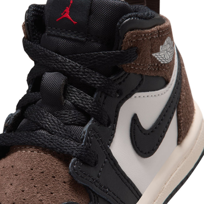 Toddler mid-top sneakers close-up: black laces, brown suede panel, red Jordan logo