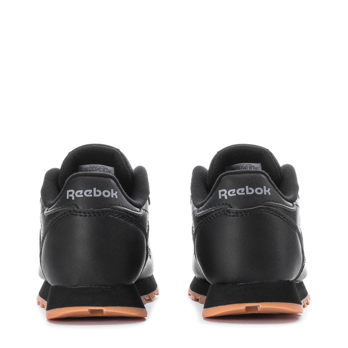 Kids black leather sneakers with Reebok heel logo and gum-toned midsole, back view.