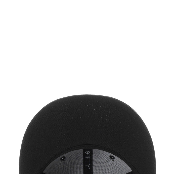 Black baseball cap top close-up with textured fabric and stitched panels
