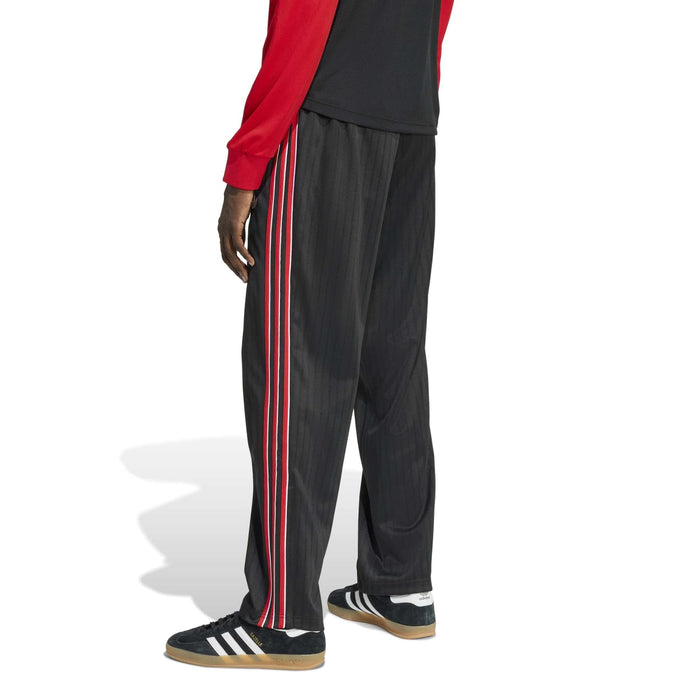 Black track pants with vertical red-and-white side stripes and tapered leg