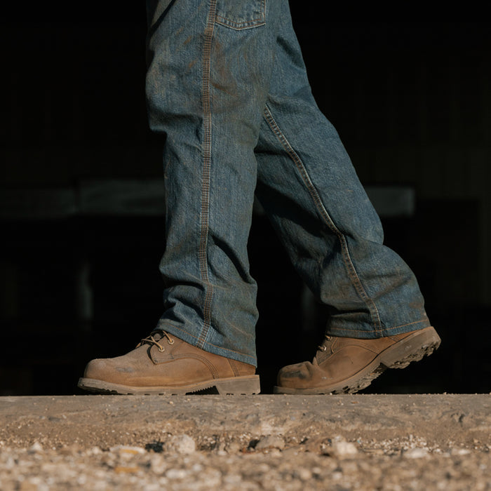 Brown work boots with blue jeans, side view, lace-up closure and thick sole