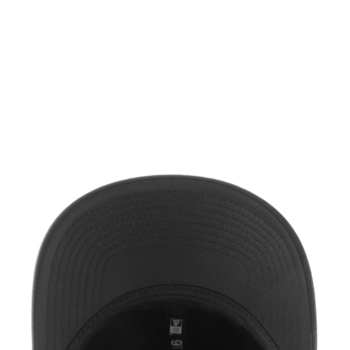 Black baseball cap brim close-up with textured stitching and seam lines