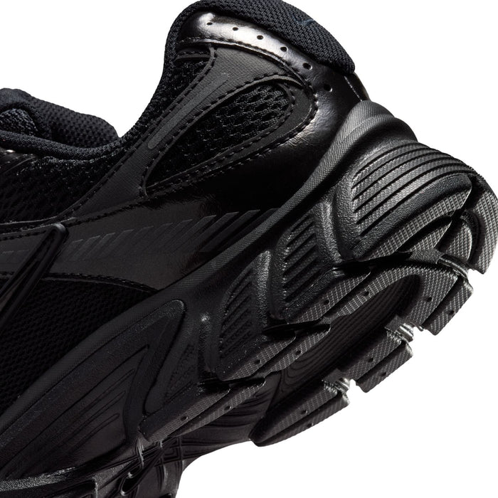 Black sneaker side close-up with rubber ridges and textured tread pattern on sole.