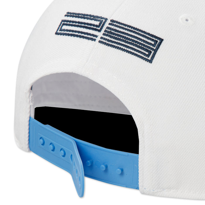 Youth snapback cap close-up, blue strap, black lining, flag logo on white crown