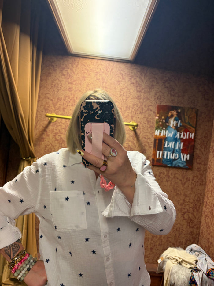Camille & Co. Reach for the Stars blouse featuring a flowy fabric with star pattern and long sleeves, displayed on a hanger.