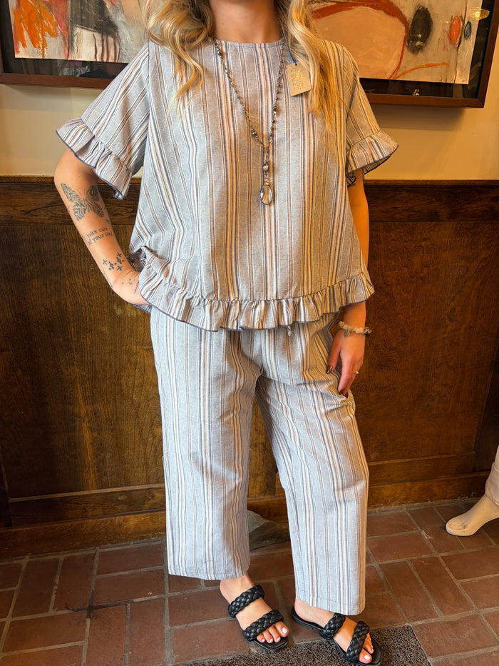 Camille & Co. Earn Your Stripes top featuring a striped pattern and casual fit, displayed on a hanger against a neutral background.