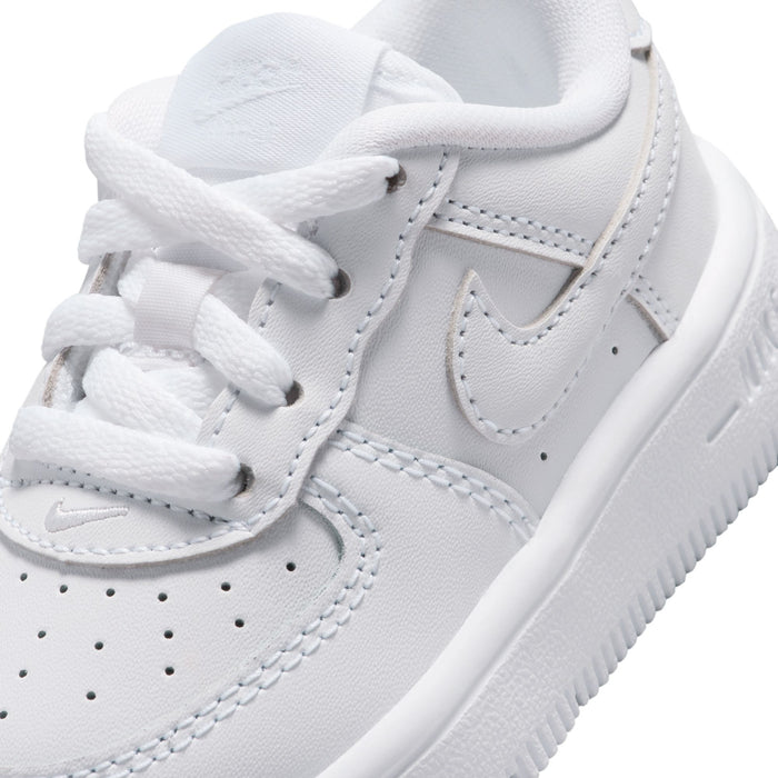 Close-up of toddler white low-top sneaker with swoosh detail and white laces