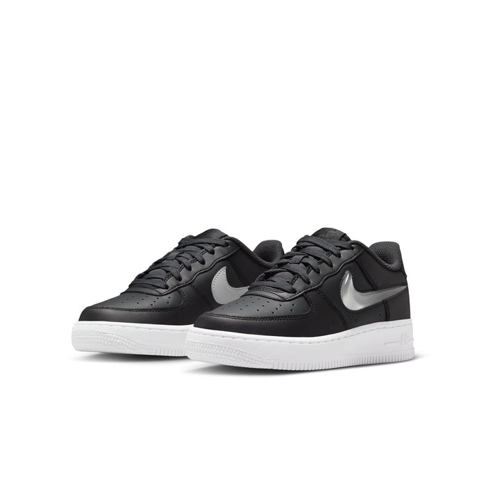 Pair of youth low-top sneakers with lace-up closure, dark uppers, white soles