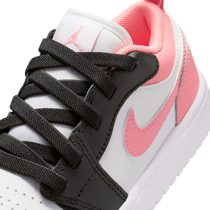 Kids' low-top sneakers close-up: black laces, white leather, and pink swoosh