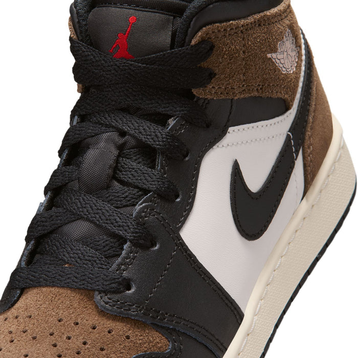 Close-up of youth sneaker upper with black laces, brown suede, white panel, black swoosh.