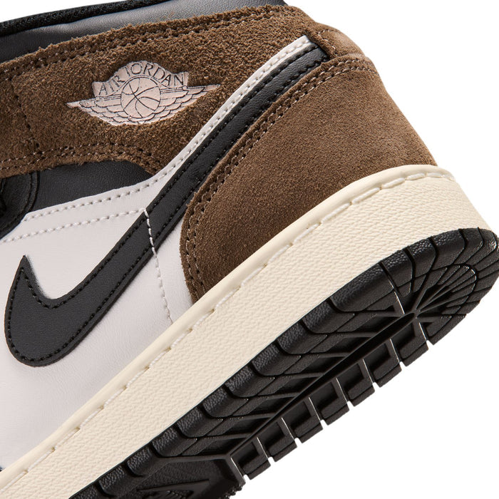 Close-up of youth sneaker lateral side with winged logo, black swoosh, brown suede.