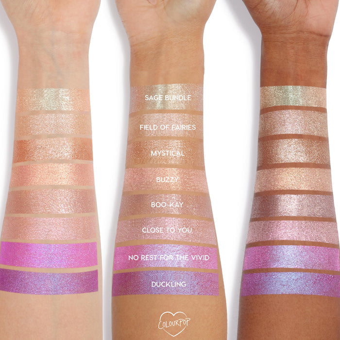 Colourpop Big Ego Jelly Much Shadow swatched on three arms, showing shimmering eyeshadow shades from soft champagne and peach to vivid pink and lavender, demonstrating pigment and finish across different skin tones.