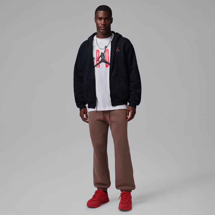Men's black zip-up hoody with hood, layered over a white tee; model standing.