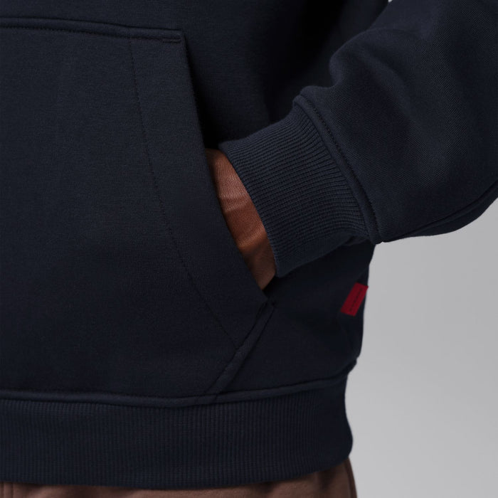 Black zip-up hoody sleeve and cuff ribbing with kangaroo pocket seam; close-up.