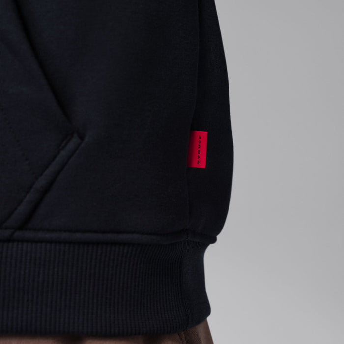 Black zip-up hoody sleeve hem and side label patch; close-up.