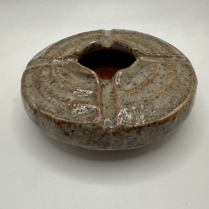 Round ceramic ashtray with dark speckled glaze and wide center opening.