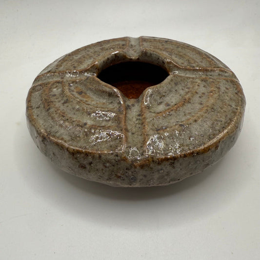 Round ceramic ashtray with dark speckled glaze and wide center opening.