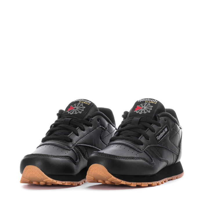 Kids black leather low-top sneakers with Reebok branding and gum soles, front view.