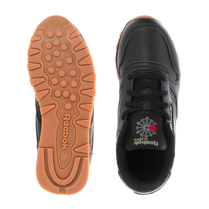 Kids black leather sneakers: gum outsole tread and black heel, pair soles view.