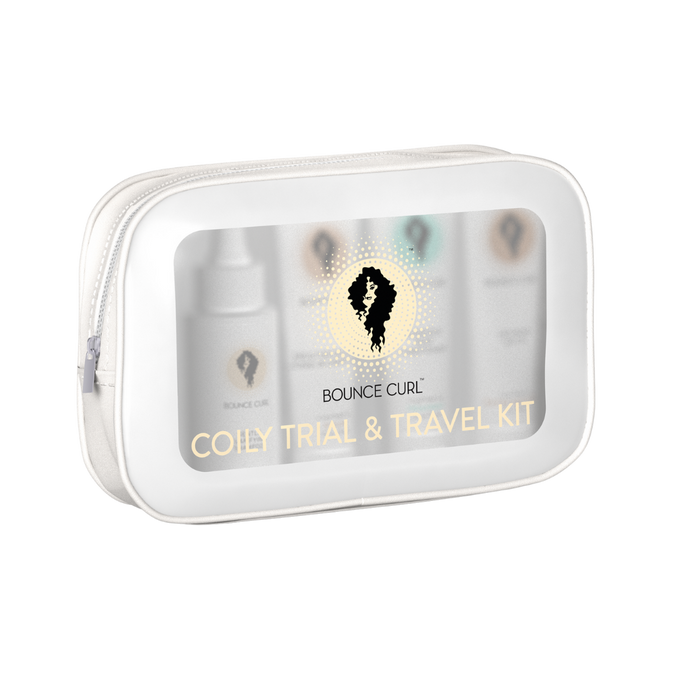 A clear zip pouch labeled Bounce Curl Coily Trial & Travel Kit containing several small product bottles