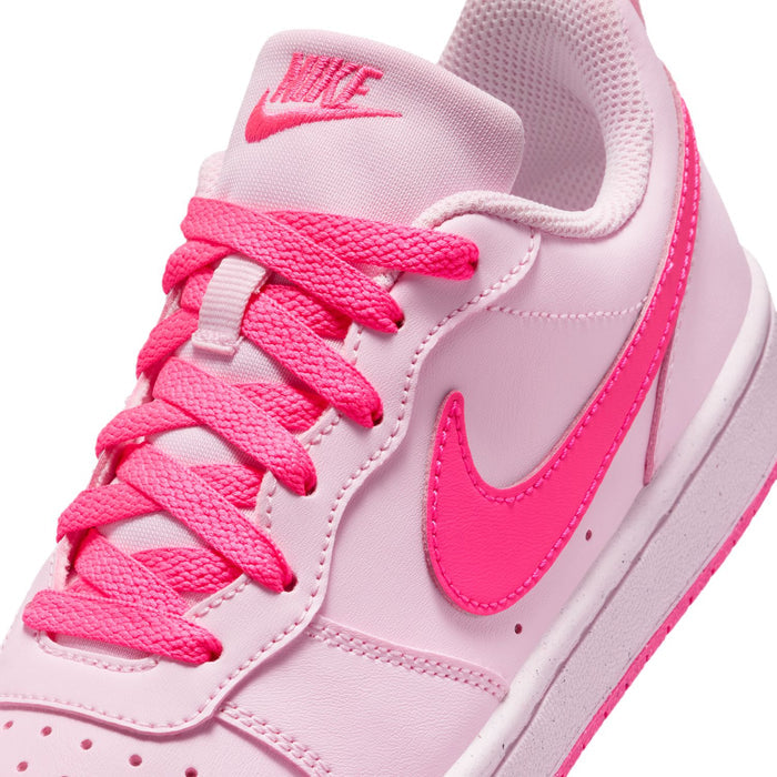 Youth pink low-top sneaker close-up with pink NIKE logo on tongue and lace-up detail