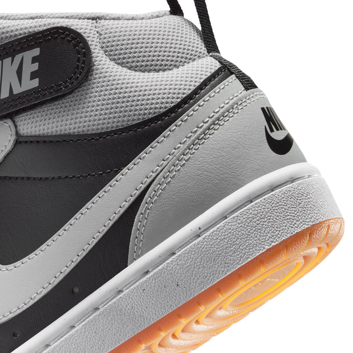 Youth sneaker side detail: black Swoosh, gray overlays, and orange-tinted sole edge.