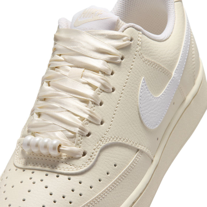 Close-up of women’s cream lace-up Nike sneakers with stitched Swoosh and padded collar