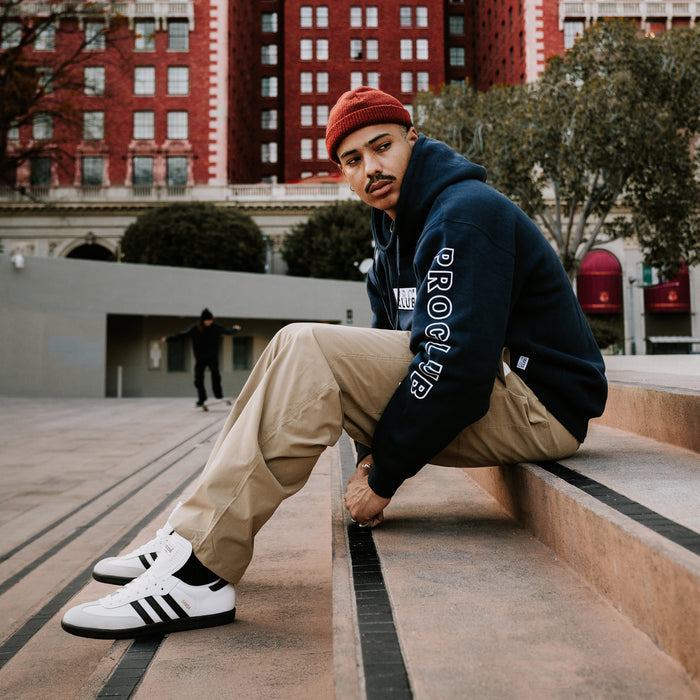 Navy hoodie worn by man, embroidered front logo and sleeve graphic