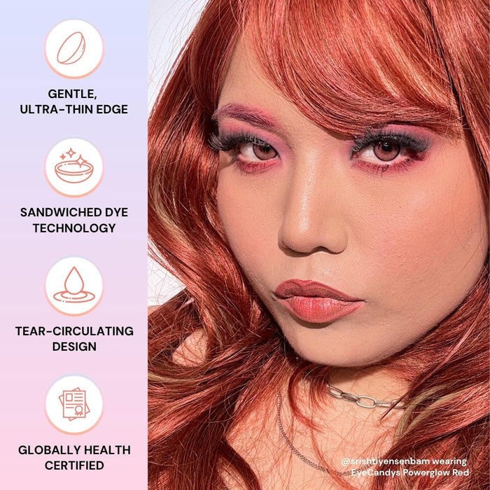 A person with long, wavy red hair and bold pink makeup looks at the camera. Beside them are icons highlighting EyeCandys Powerglow Reddish Pink contact lens features: gentle, ultra-thin edge, sandwiched dye tech, UV protection, and global certification.