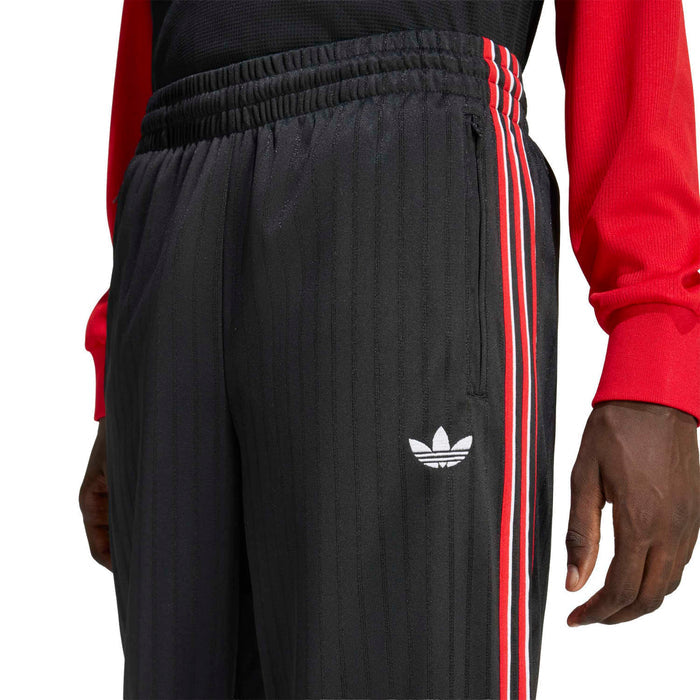 Black track pants detail: elastic waistband and red-and-white triple side stripe