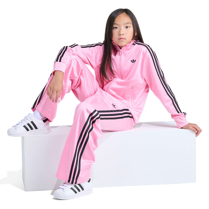 Youth pink track jacket with black sleeve stripes, model seated
