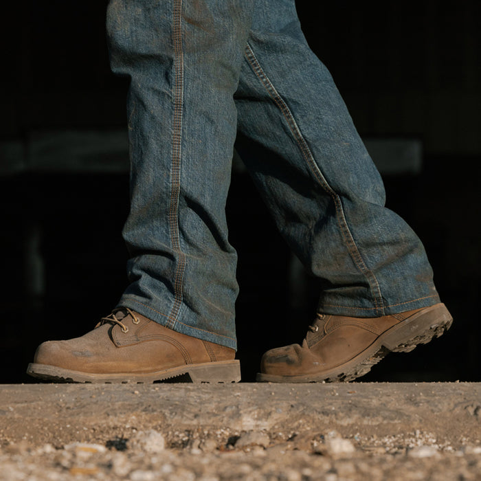 Brown work boots worn with blue jeans, lace-up front and rugged sole