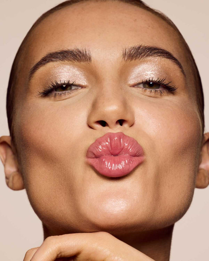 medium skin toned model wearing gloss bomb cream in shade fenty glow