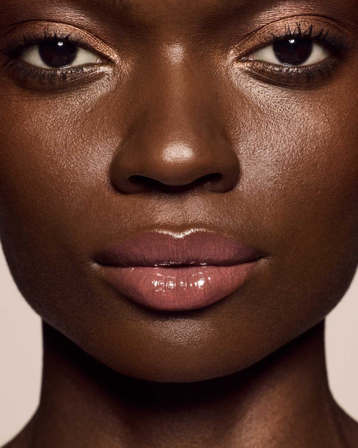 deep skin toned model wearing gloss bomb cream in shade fenty glow