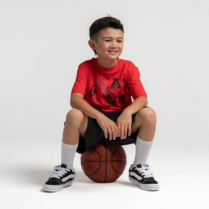Red youth graphic T-shirt with front sports print, worn by seated youth