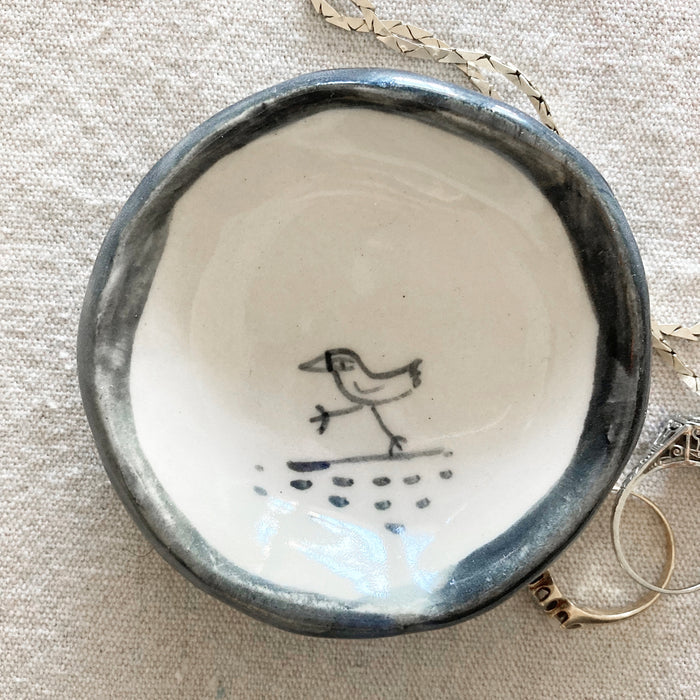 Handmade ceramic bird trinket dish with blue rim and bird-and-raindrop design