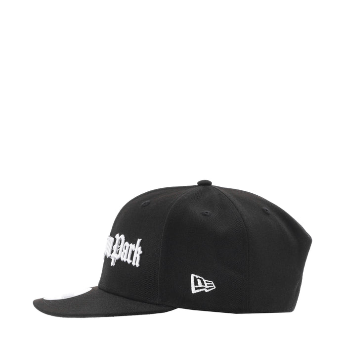 Black baseball cap with white side logo and small rectangular front patch
