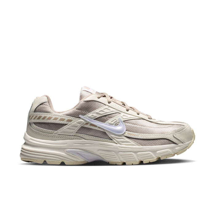 Women's cream and tan lace-up running sneakers, side view with swoosh detail