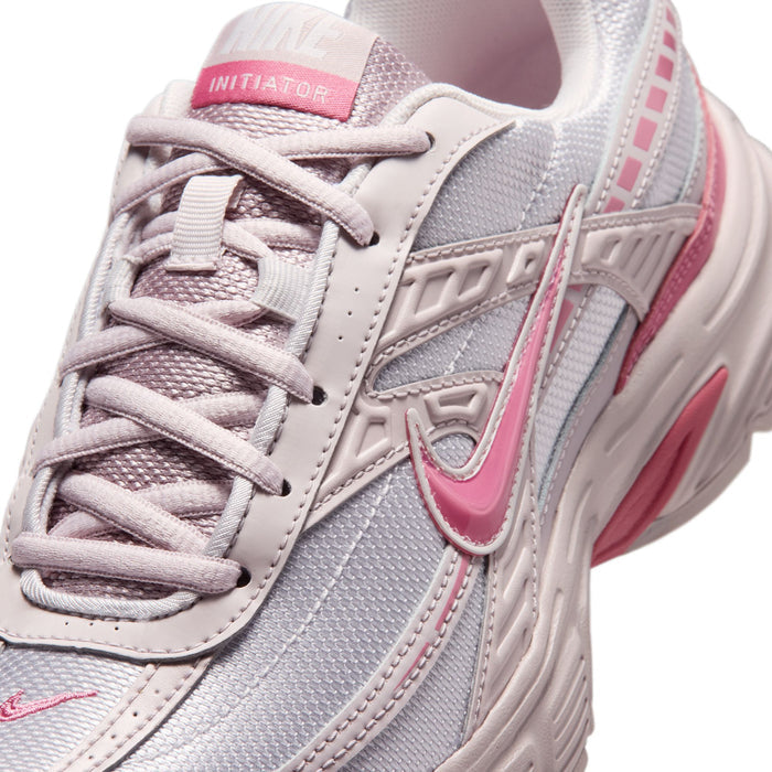 Close-up of light gray and pink women's sneaker with laces and swoosh