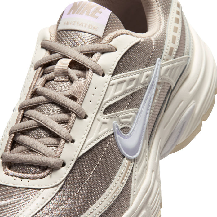Women's lace-up sneaker close-up with Nike swoosh and mesh panel in cream and tan