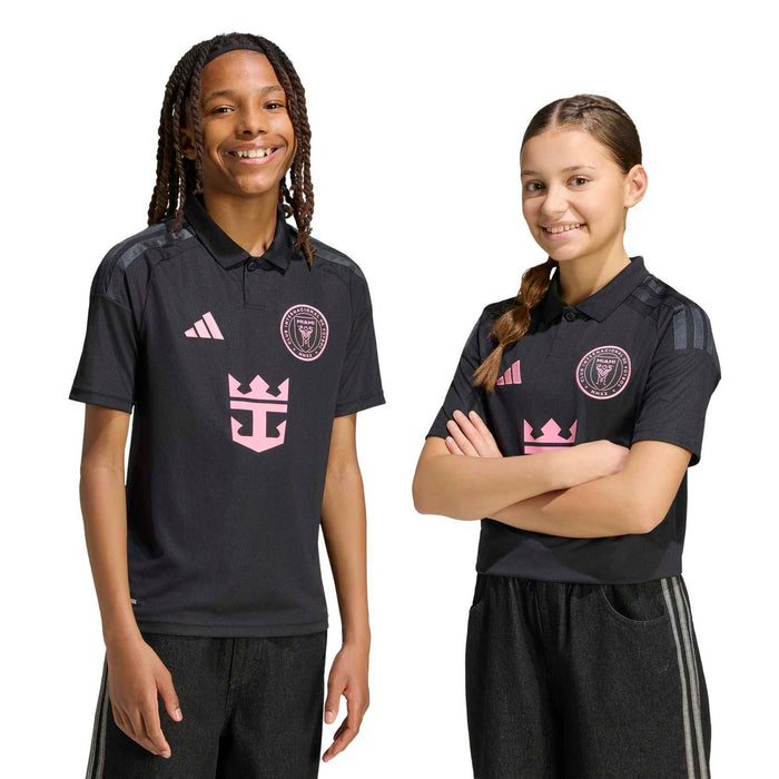 Youth black soccer jersey with pink logo on chest, worn by two kids