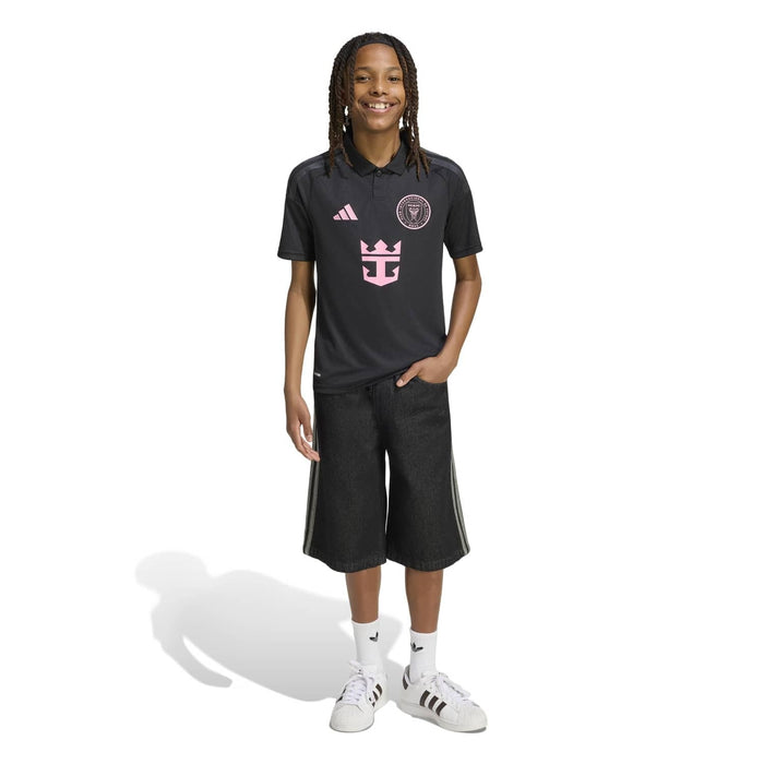 Youth black away soccer polo-style jersey with pink chest crest, worn on model