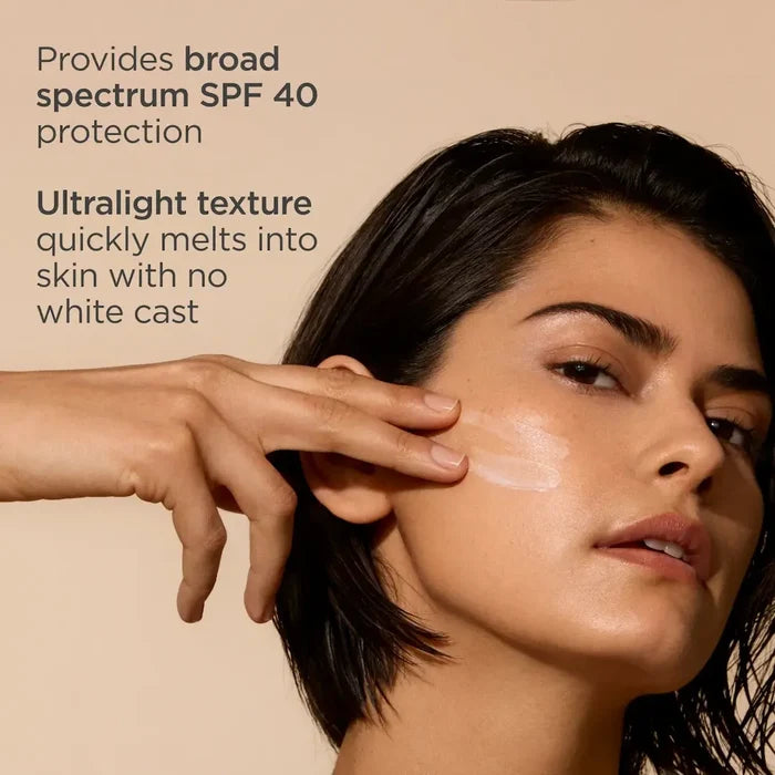 Woman applying lightweight ISDIN Fusion Water MAGIC SPF 40 sunscreen to cheek, no white cast