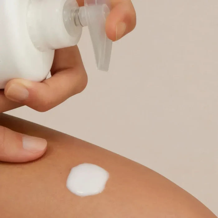 Applying ISDIN Uradin Lotion 10 to skin with white moisturizing lotion