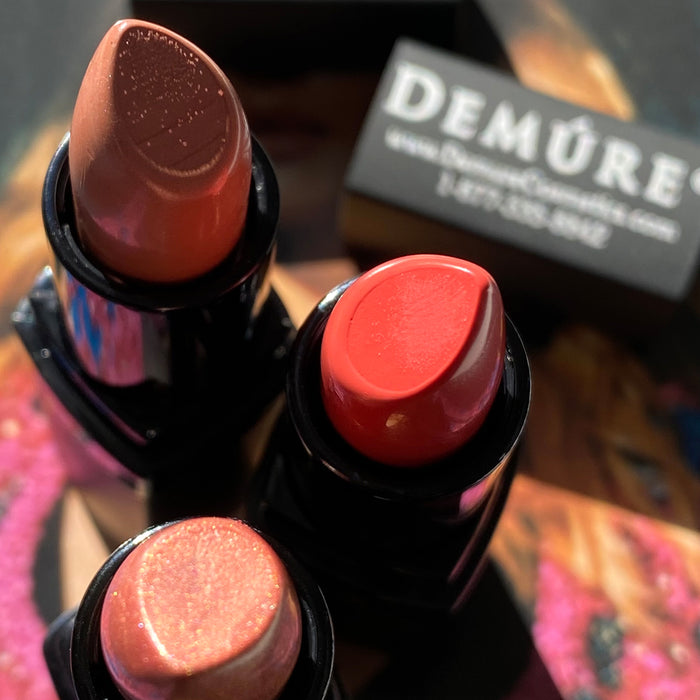 Bird's eye view showing three open Demure lipsticks and the colors