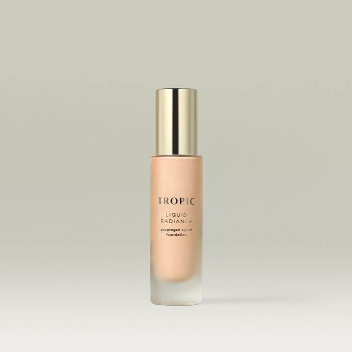 A frosted glass bottle of Tropic Liquid Radiance adaptogen serum foundation in shade 2 with a gold cap, standing upright against a soft neutral background.
