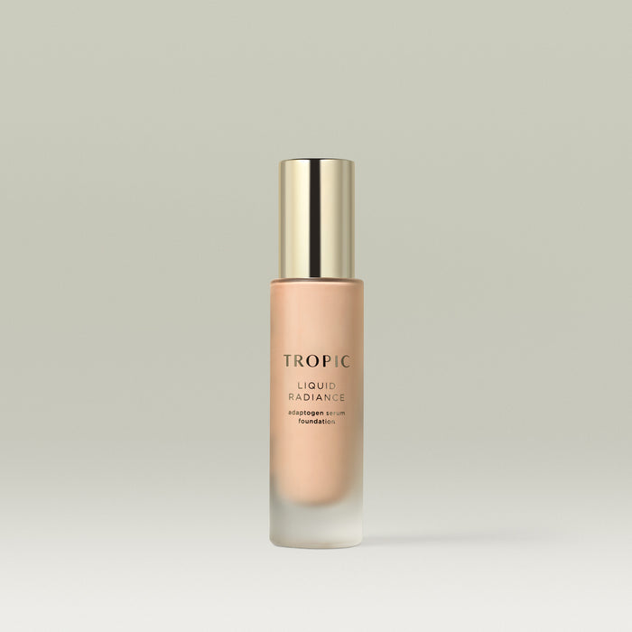 A frosted glass bottle of Tropic Liquid Radiance adaptogen serum foundation in shade 3 with a gold cap, standing upright against a soft neutral background.