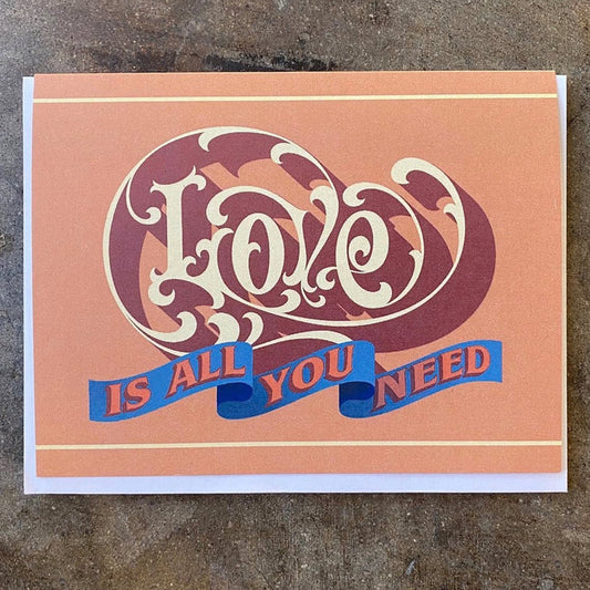 Love-themed greeting card, purple heart graphic and blue text: 'IS ALL YOU NEED'.