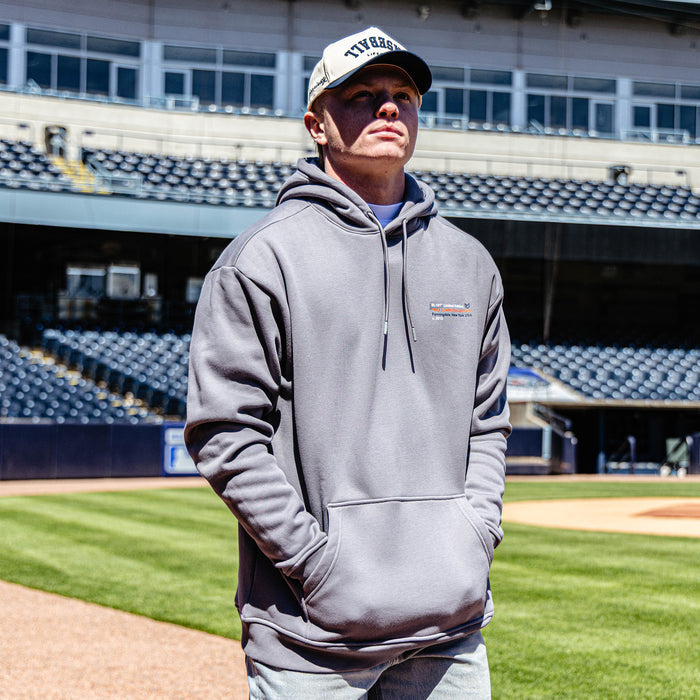 Person wearing a gray hoodie and cap on a baseball field