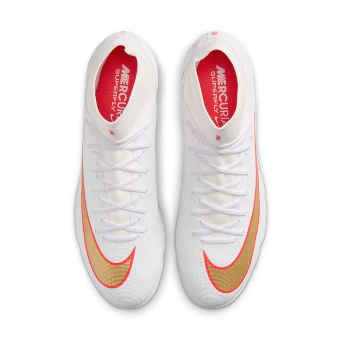 Pair of white Nike turf soccer cleats showing red insoles and orange swoosh toe